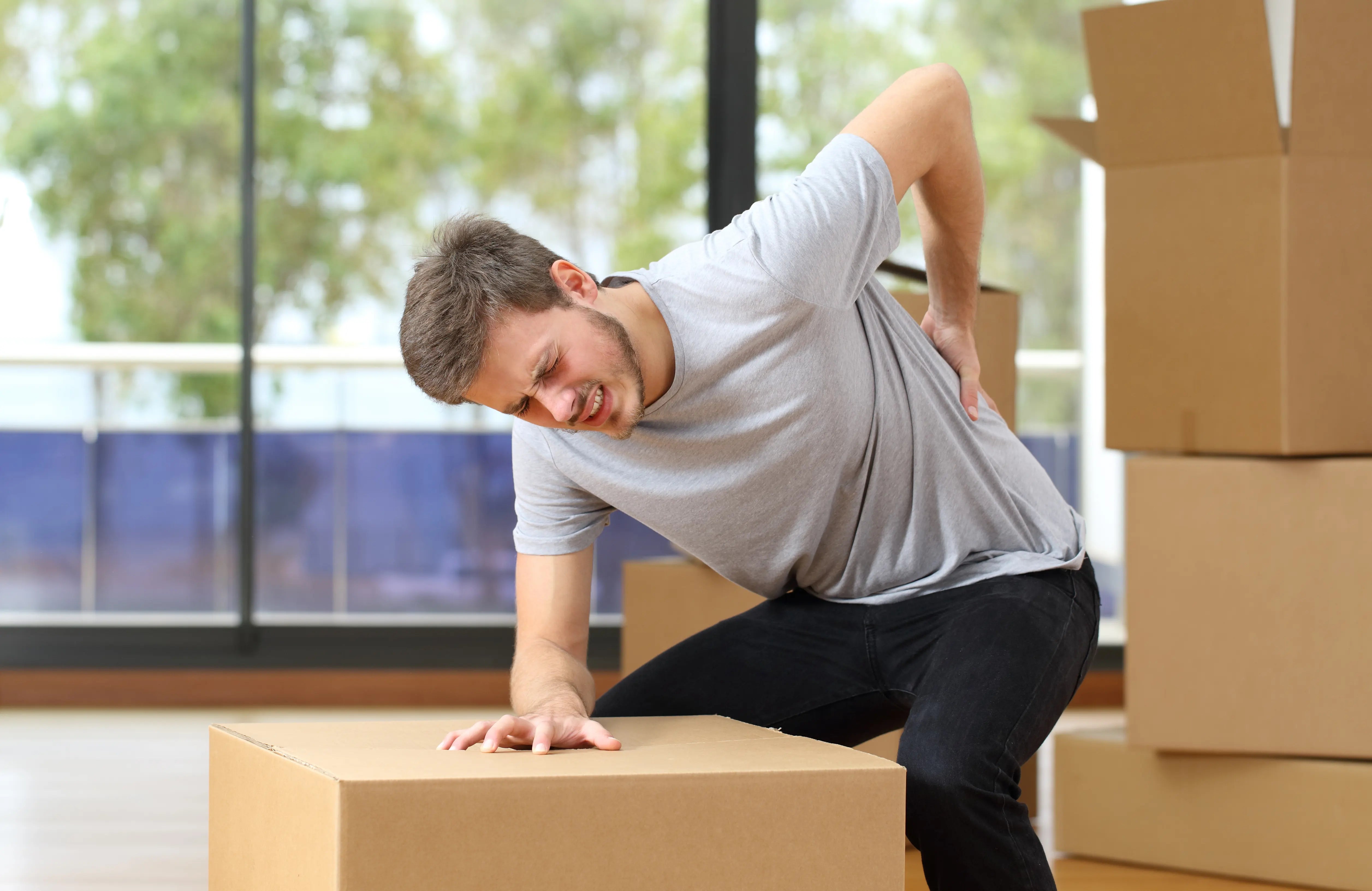 A man has a sore back from moving and carrying heavy boxes 